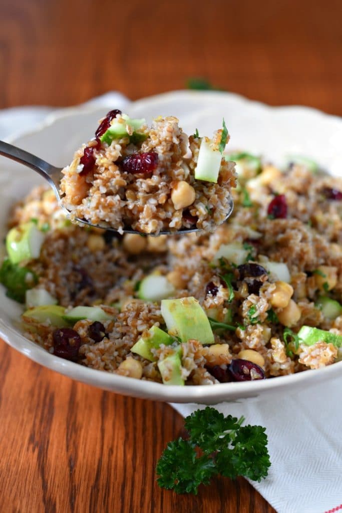 a silver spoon serving bulgur salad from a white serving bowl