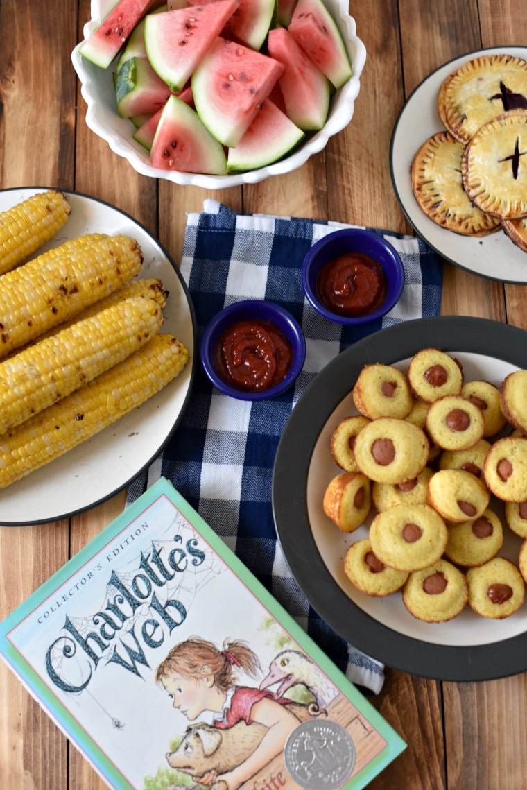 A wooden table with a meal on top and the book Charlotte's Web