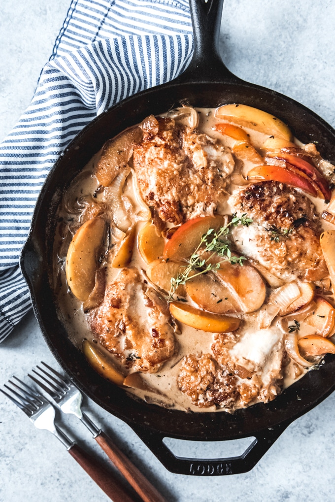 cast iron skillet with chicken and apple slices