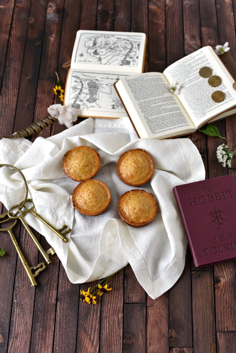 Books, keys, coins, flowers, a white towel, and honey cakes arranged on a wooden table