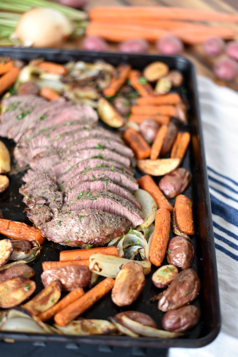 A sheet pan with sliced roast beef and roasted carrots, onions, and potatoes 