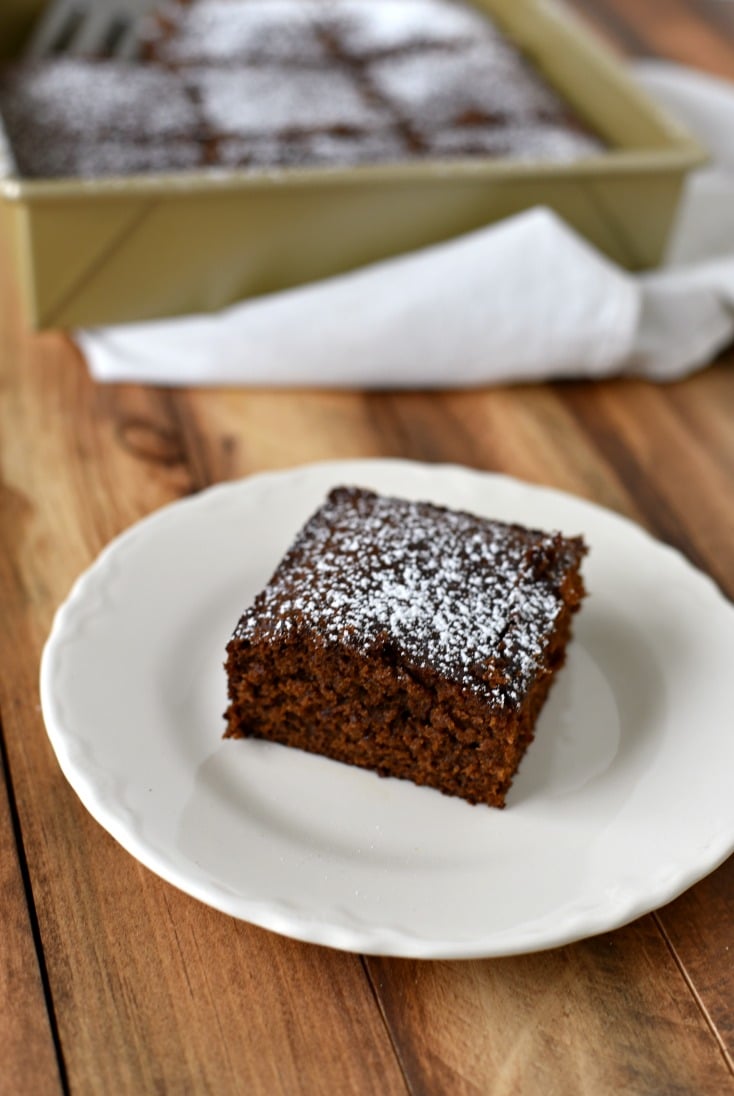 A slice of historical gingerbread cake on a white plate on a wooden table