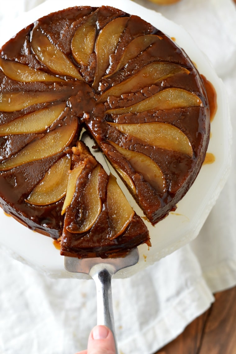 A cake server pulling a slice of pear gingerbread cake off of the cake platter