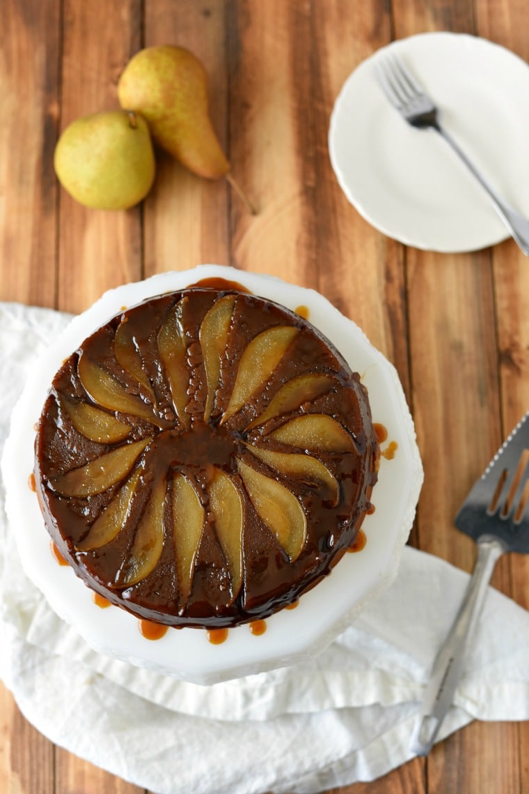 Pear gingerbread cake on a white plate sitting on a wooden table