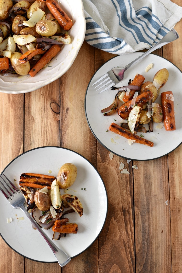 Two plates of roasted carrots and turnips on a wooden table