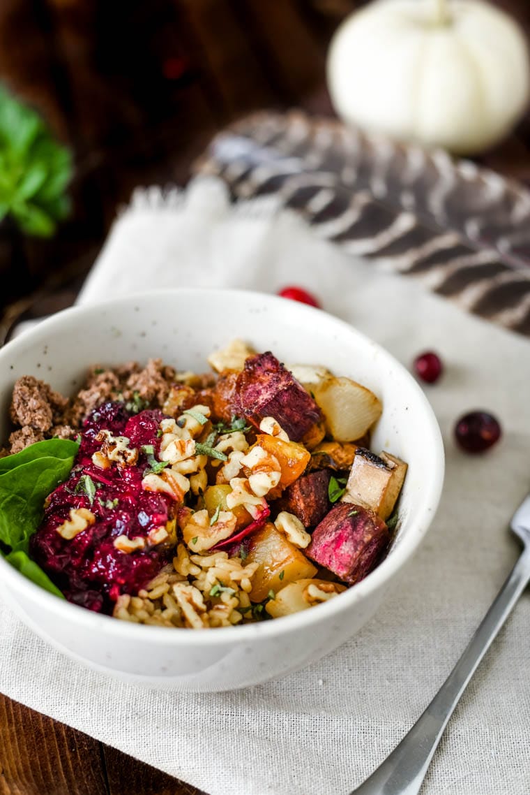 bowl filled with rice, roasted vegetables, ground bison, spinach, and very sauce