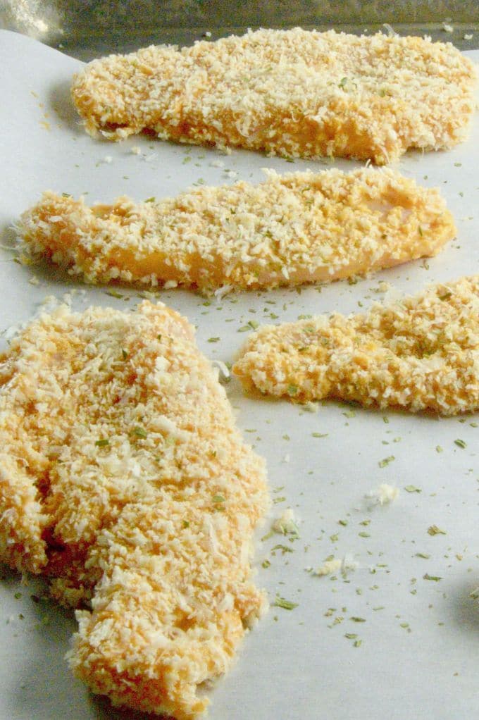 Breaded chicken tenders on a white surface.