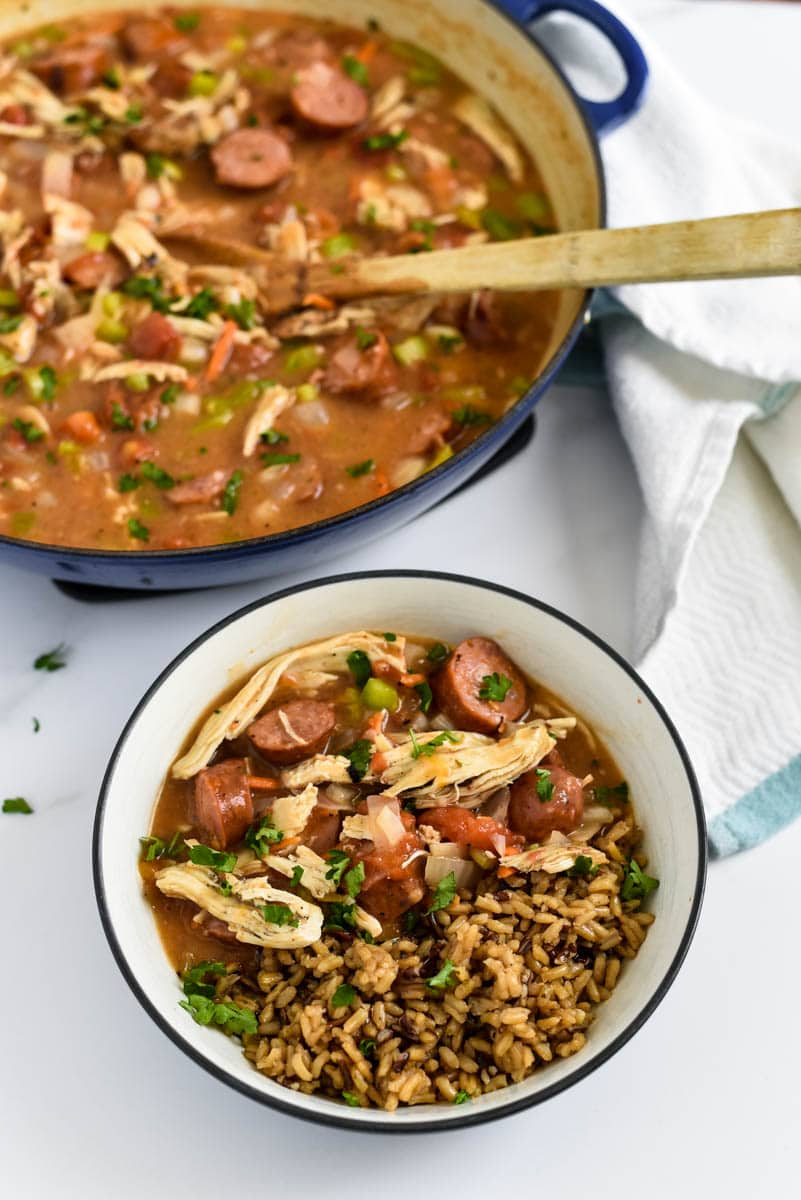 gumbo in bowl with rice next to pot with more gumbo