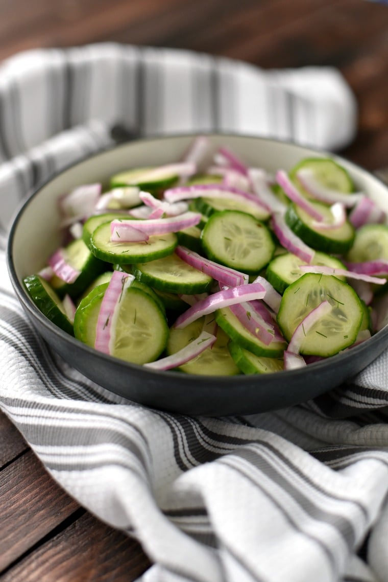 cucumber dill salad in bowl with kitchen napkin behind