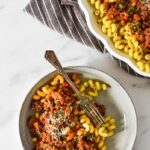 plate with pasta and beef ragu next to serving platter