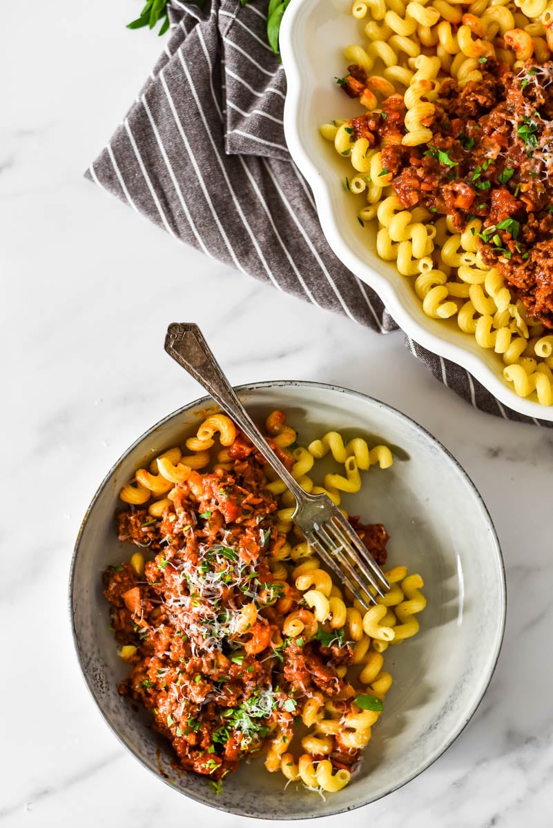 plate with pasta and beef ragu next to serving platter