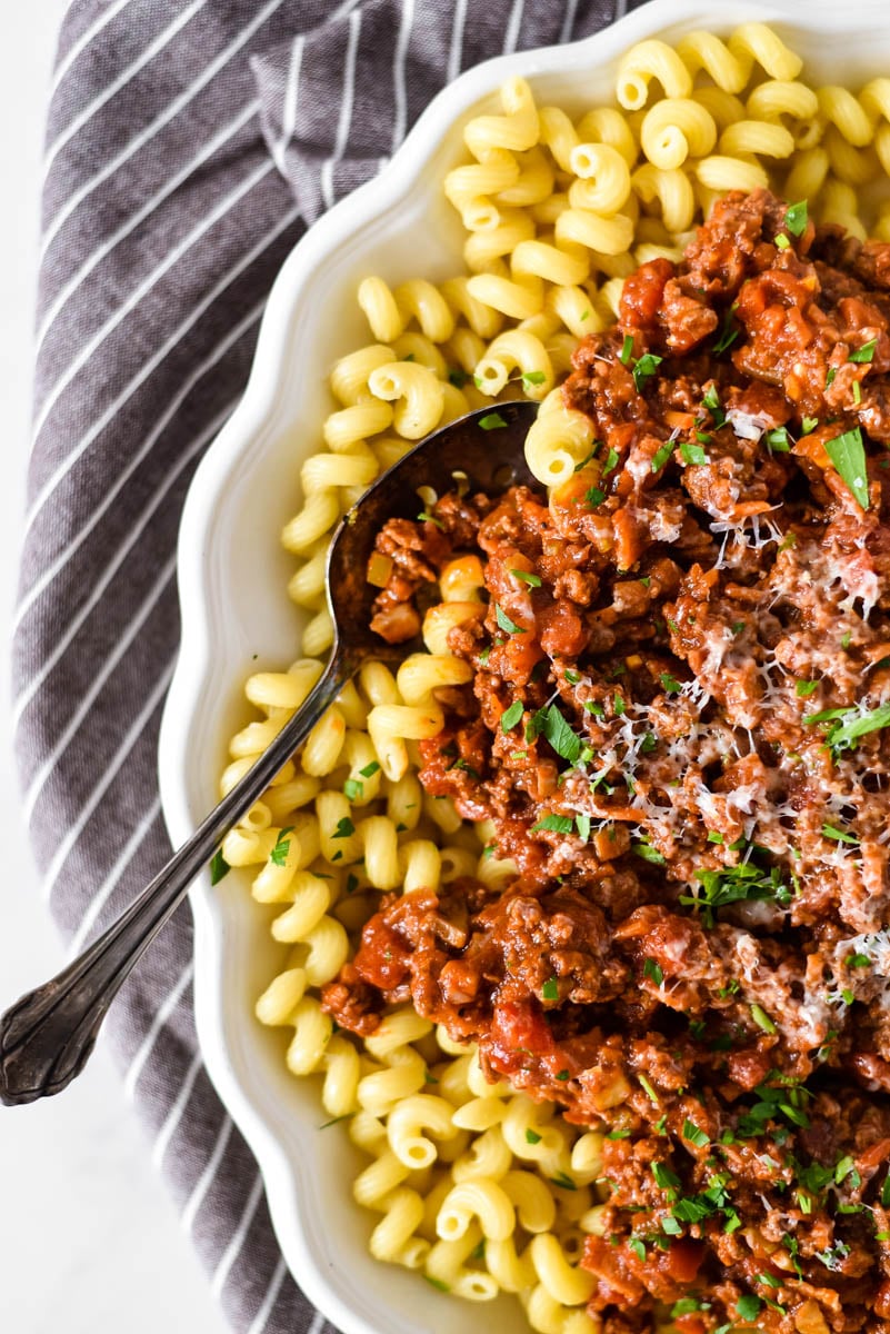 overhead close up view of beef ragu and pasta on white platter