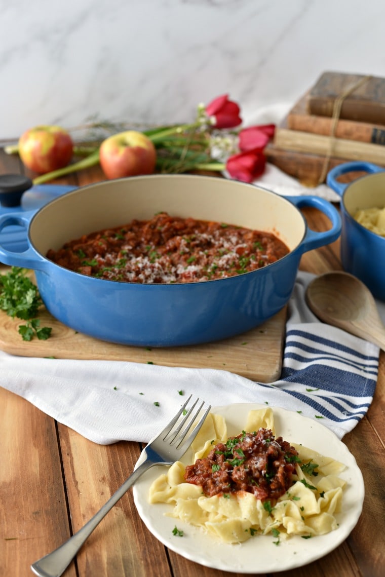 braised with homemade ragu beside plate of pasta topped with ragu