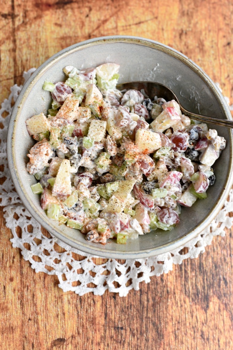 overhead view of waldorf salad in grey bowl with serving spoon