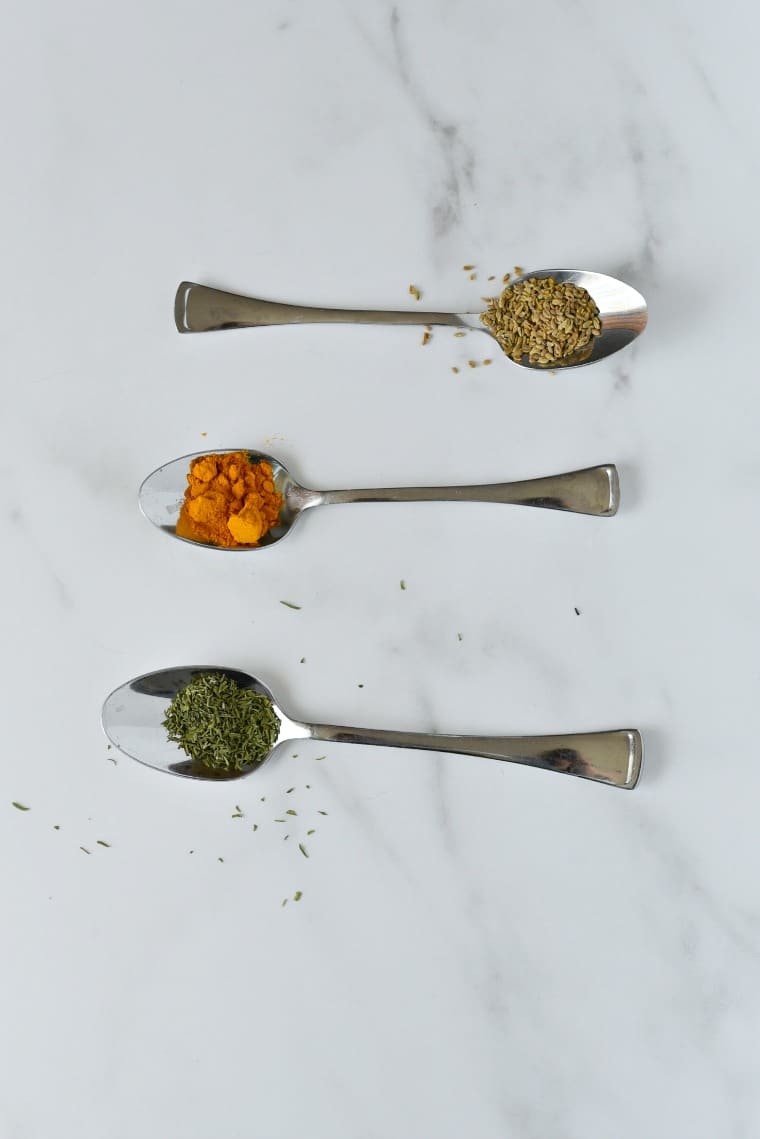 three spoons with dried parsley, turmeric, and oregano on them