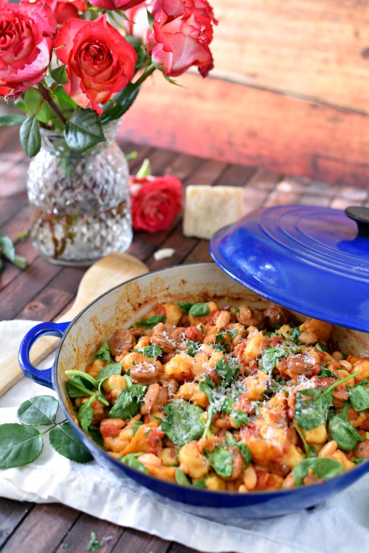gnocchi skillet with sausage and spinach and rose in background