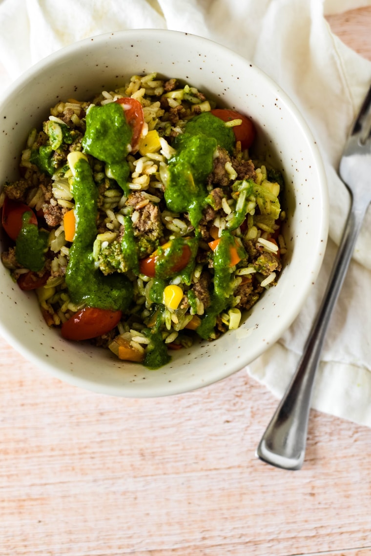 white bowl showing ground beef with rice and chimichurri sauce on white napkin