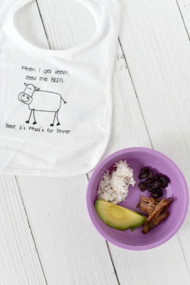 baby bib next to purple bowl filled with toddler bites of food