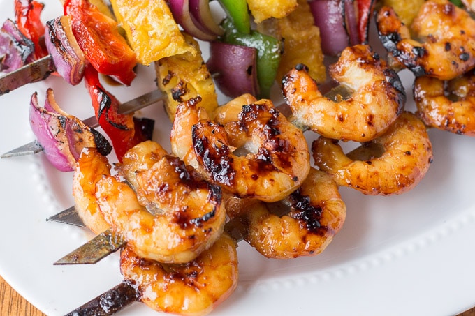 A plate of food, with Shrimp Skewers and grilled vegetables