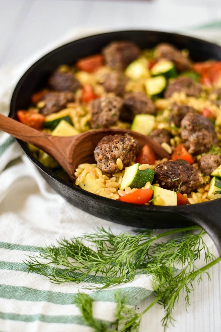 greek meatballs in cast iron skillet with orzo and veggies