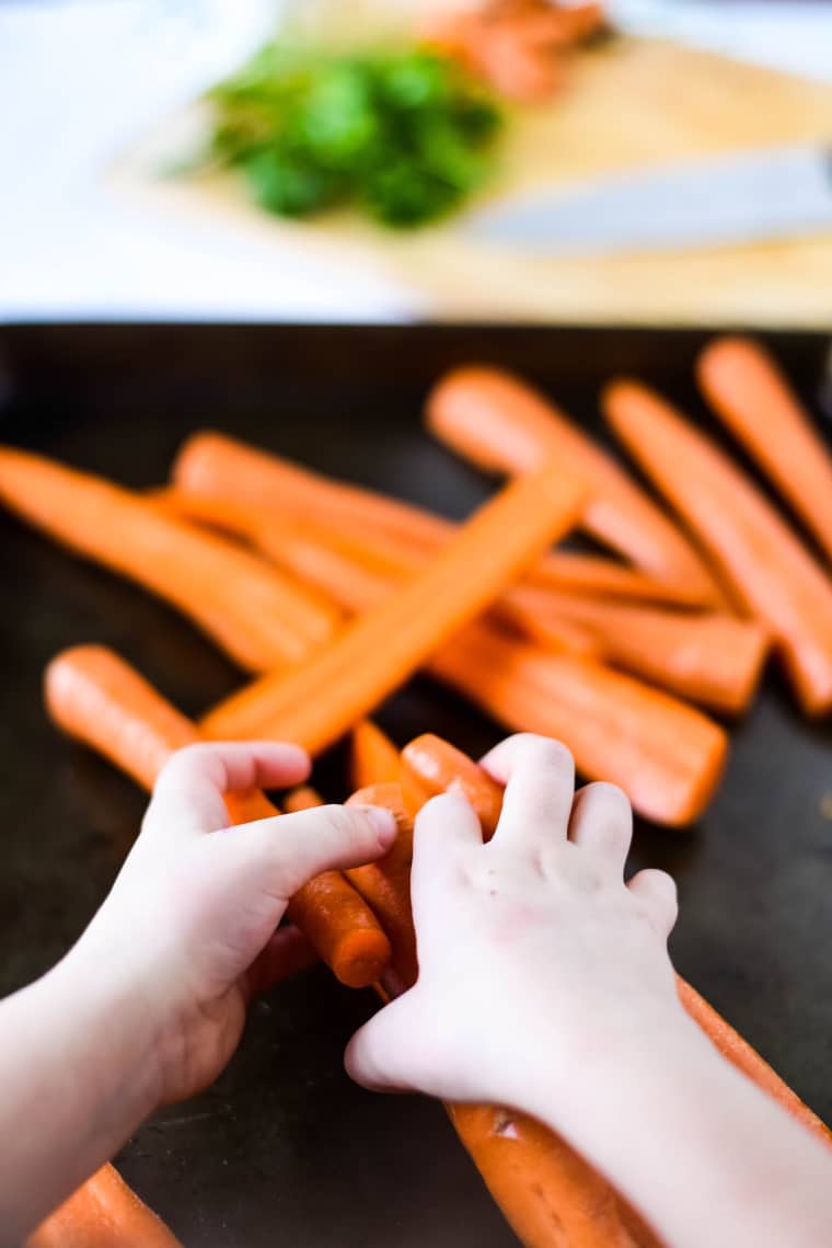 child helping to make easy roasted carrots