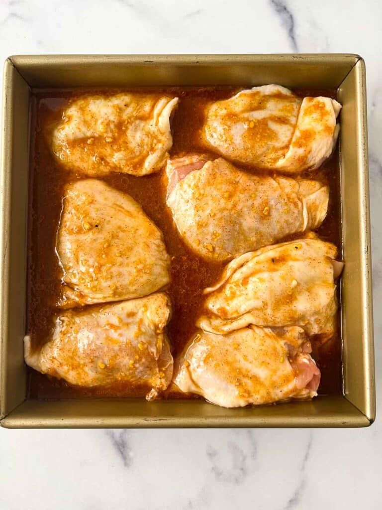 skin on chicken thighs in square dish covered in marinade