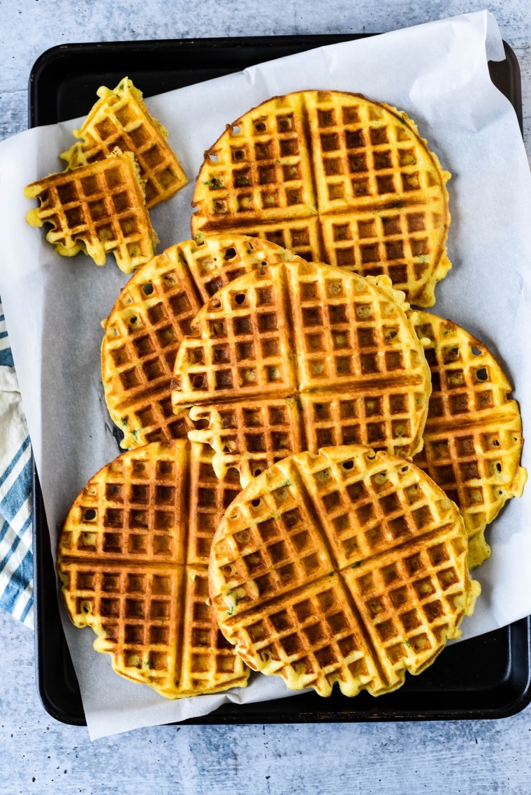 savory waffles stacked on baking sheet with parchment paper