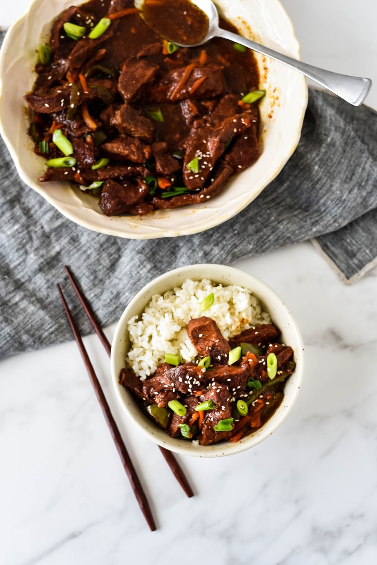 bowl of mongolian beef with rice next to serving bowl