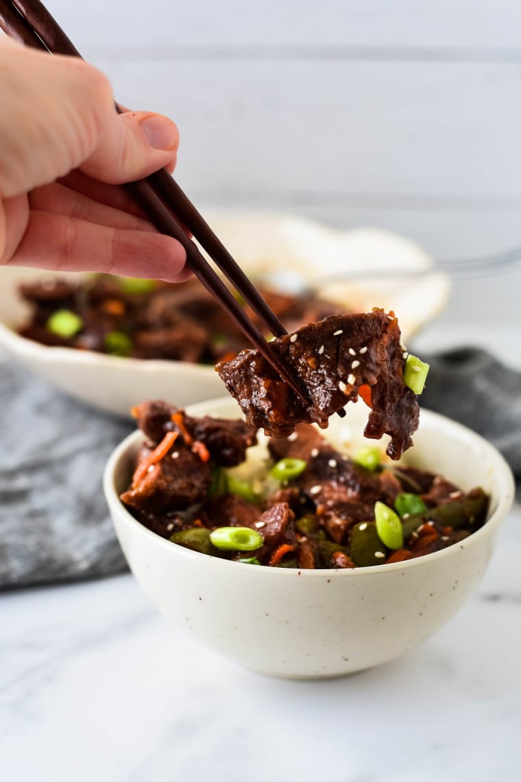 hand with chopsticks eating mongolian beef