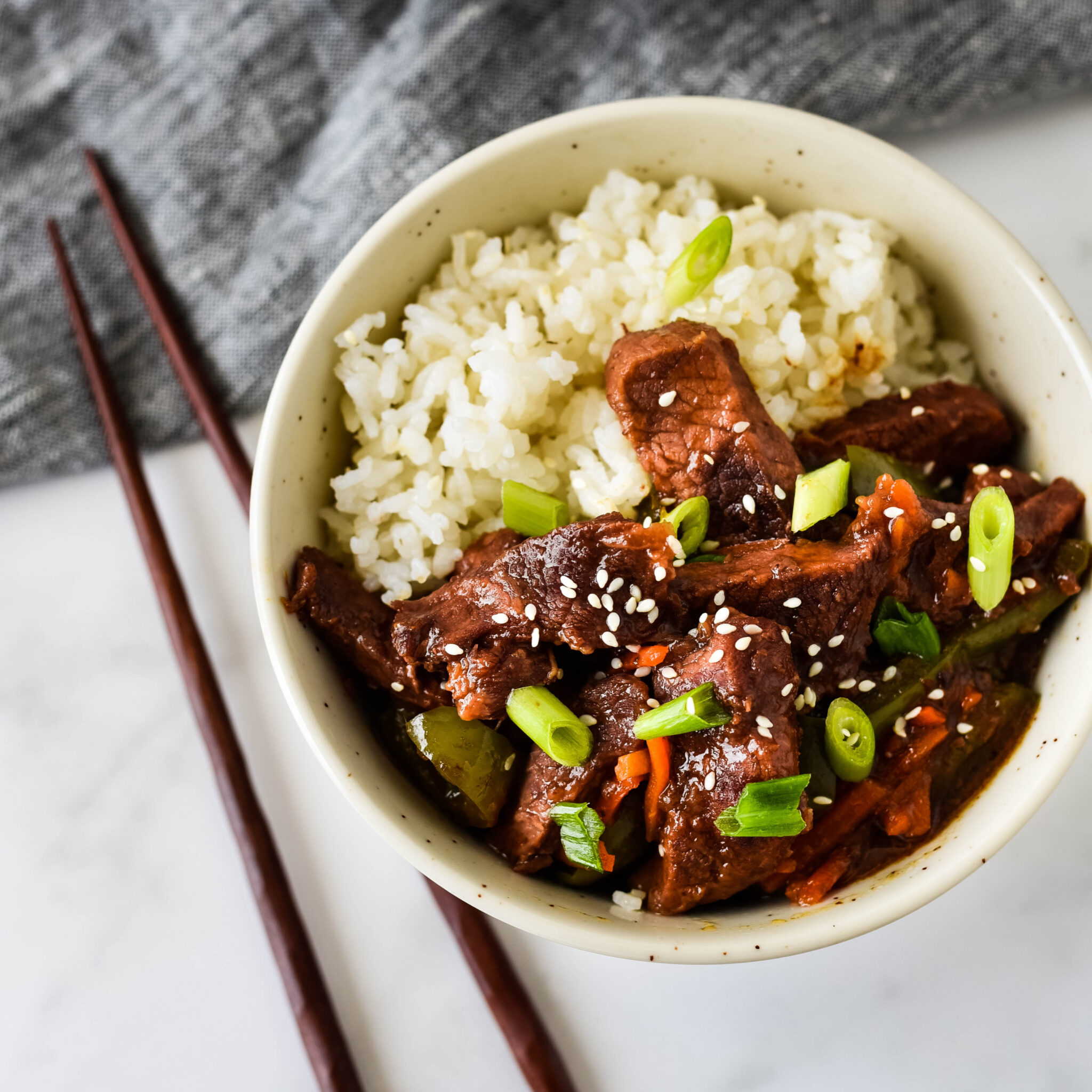 slow cooker mongolian beef in bowl with rice and chopsticks
