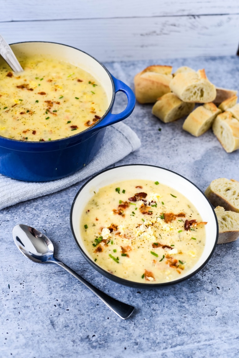 irish potato soup in bowl with bread behind