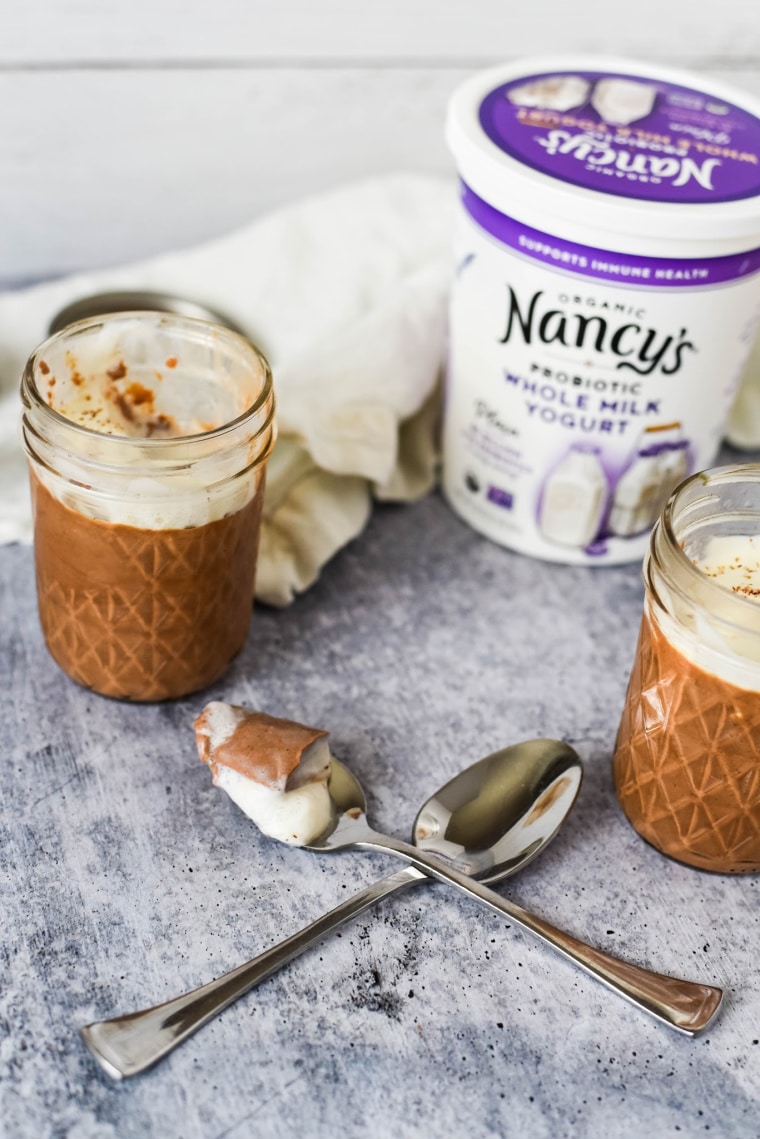 chocolate panna cotta in jars next to yogurt container and spoons