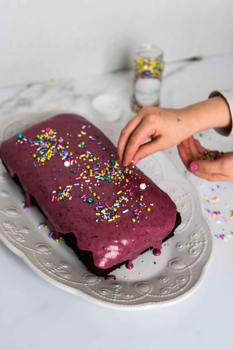 child hand putting sprinkles on chocolate wacky cake