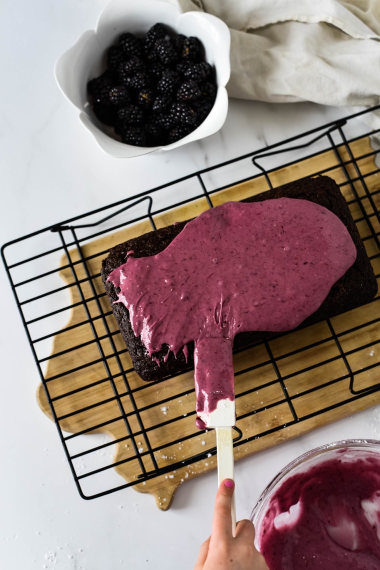 spreading blackberry icing on chocolate wacky cake