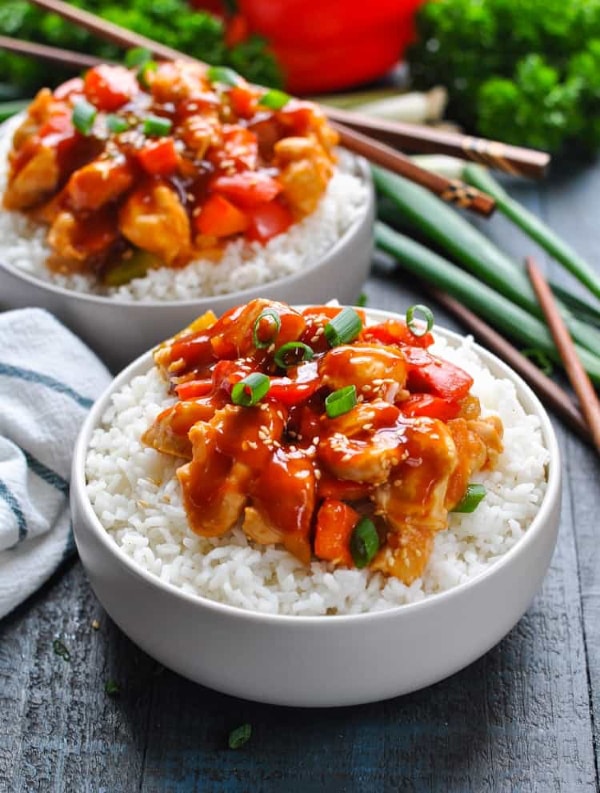 sweet and sour chicken recipe on rice in white bowls