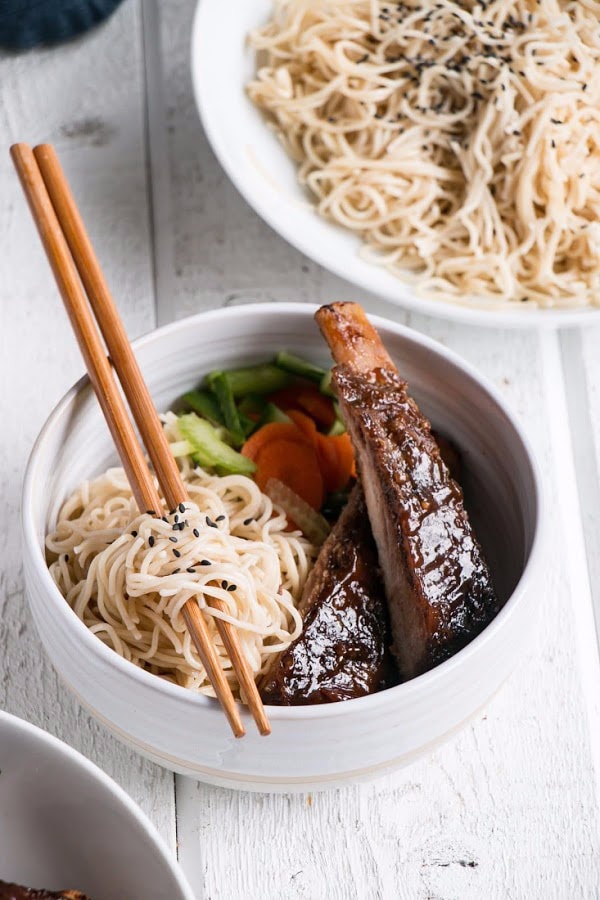 asian ribs with noodles in bowl with chopsticks