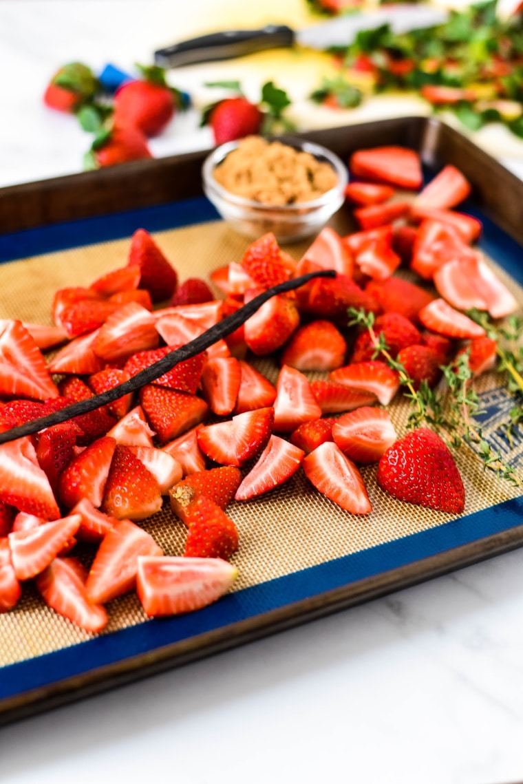 Strawberries on baking sheet with thyme and vanilla