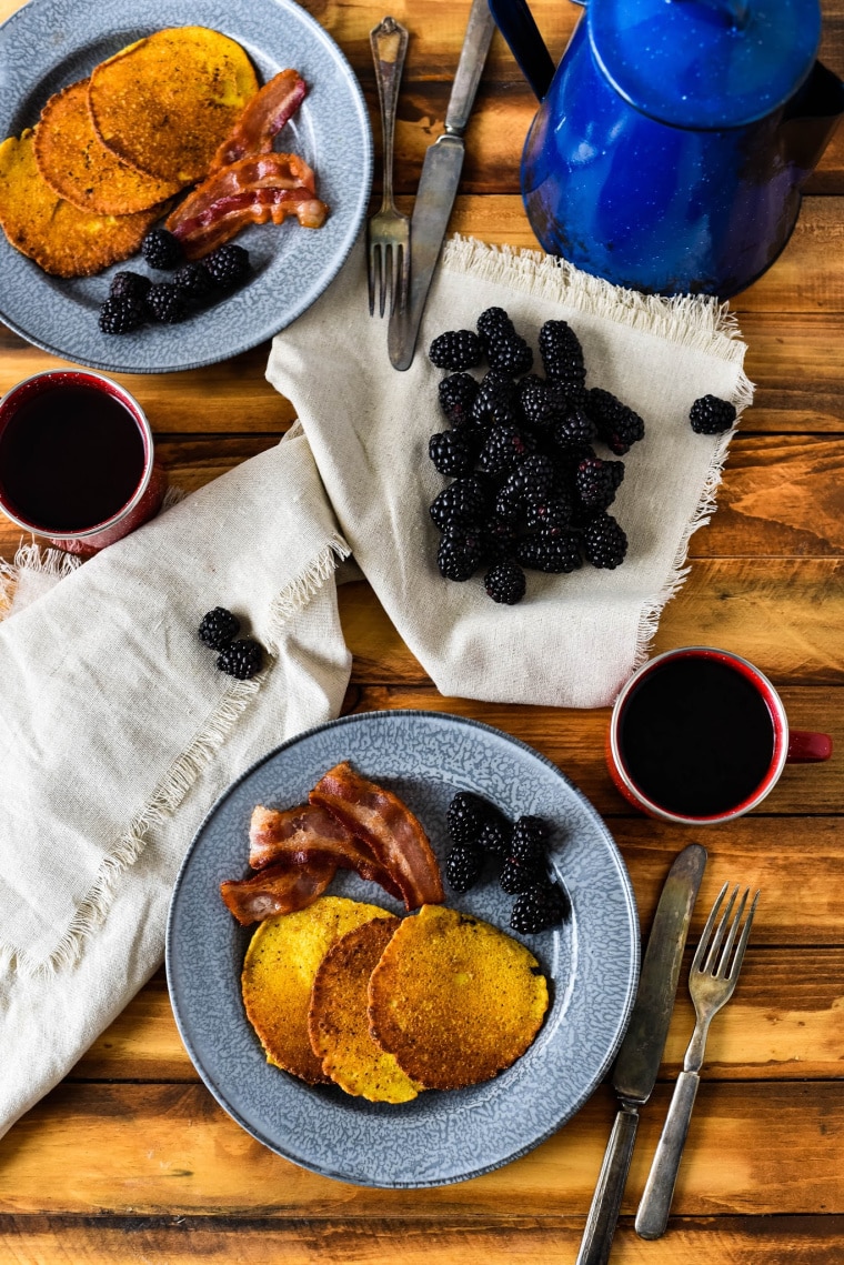 corn cakes on tin plates with bacon and blackberries