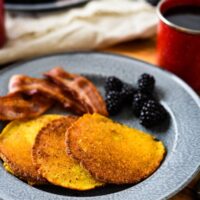 corn cakes on tin plate with bacon and blackberries