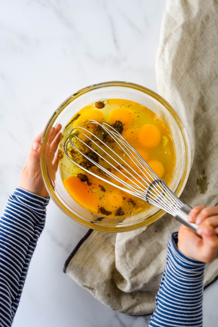 child whisking eggs in glass bowl