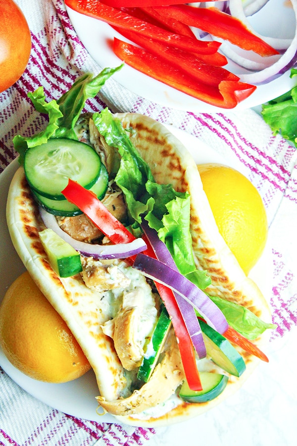 Slow-Cooker-Greek-Chicken-Gyros on table with fresh produce besides