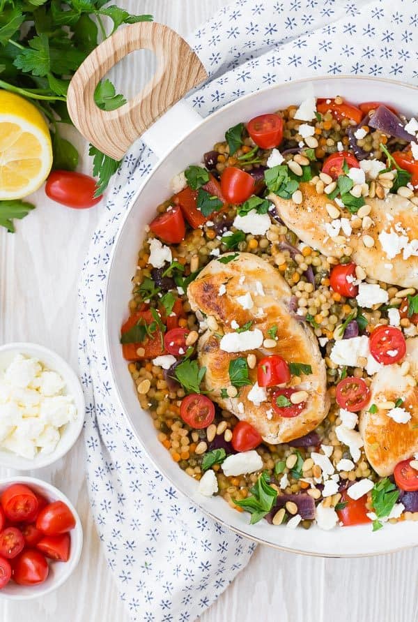 mediterranean chicken in serving bowl with feta, tomatoes and lemon