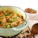 enameled cast iron pan with beef pilau, wooden serving spoon beside
