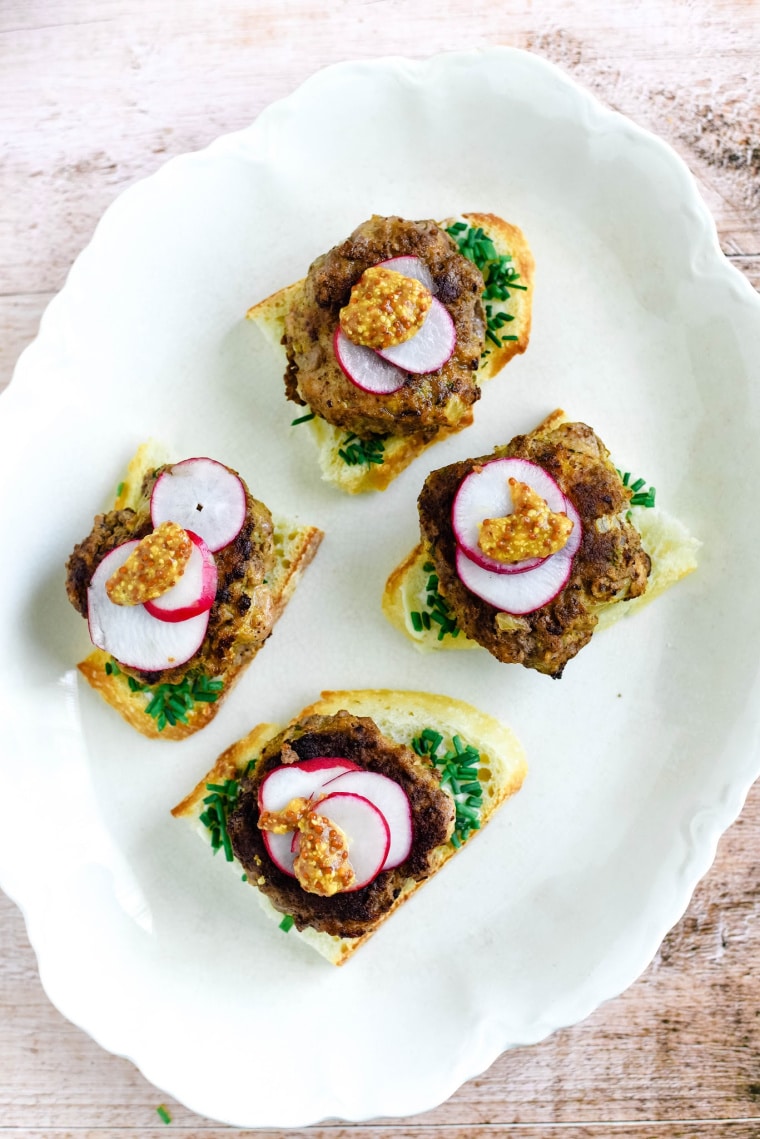 german meatball on bread with radishes and mustard on white platter