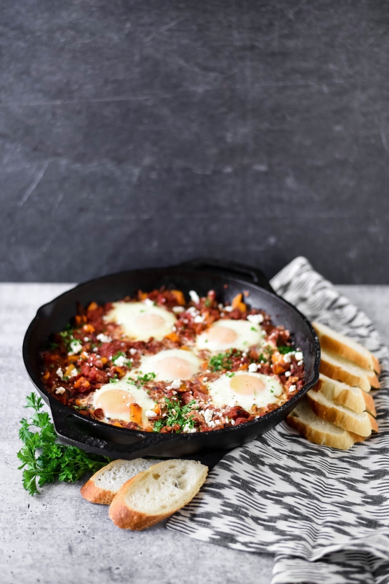 shakshuka in cast iron pan with bread beside 