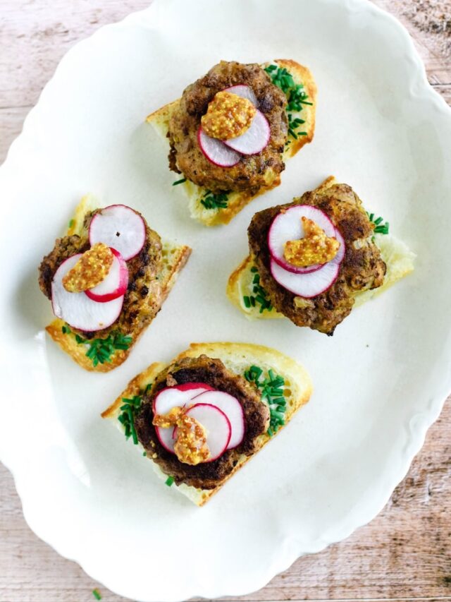 german meatball on bread with radishes and mustard on white platter
