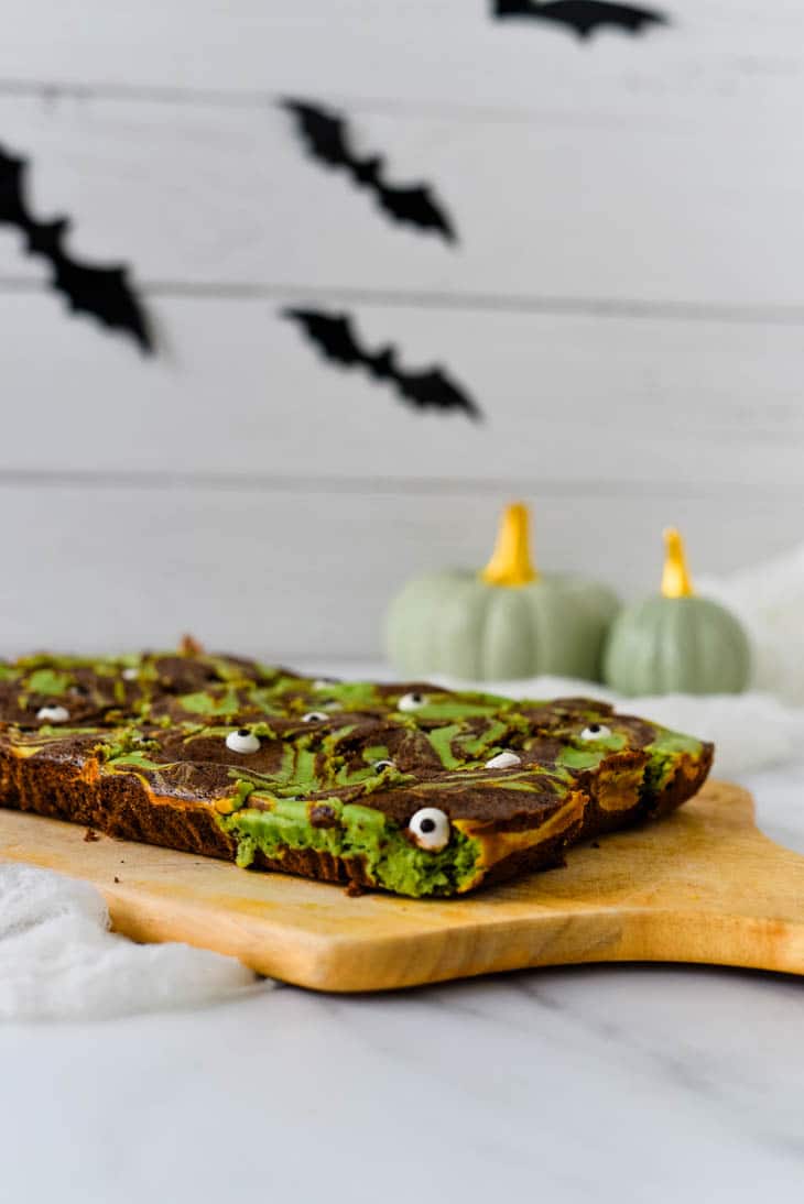 Halloween brownies on wooden cutting board with bats and pumpkins in the background