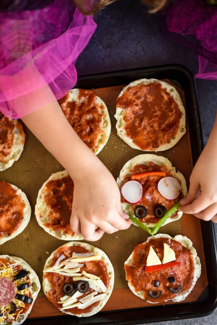 little girl using vegetables to make halloween pizzas