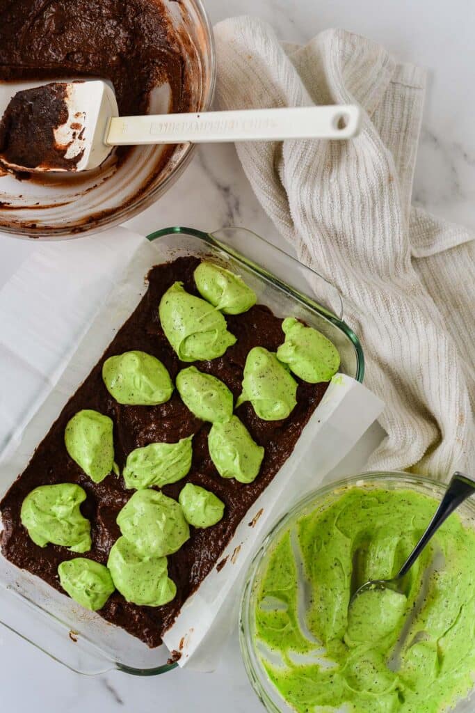 glass baking dish with brownie batter and matcha cheesecake layered