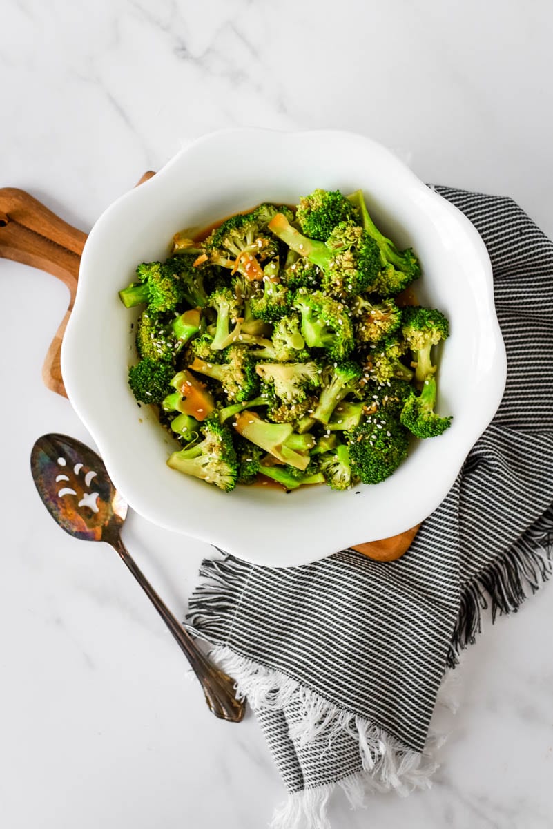 chinese broccoli in white bowl beside spoon